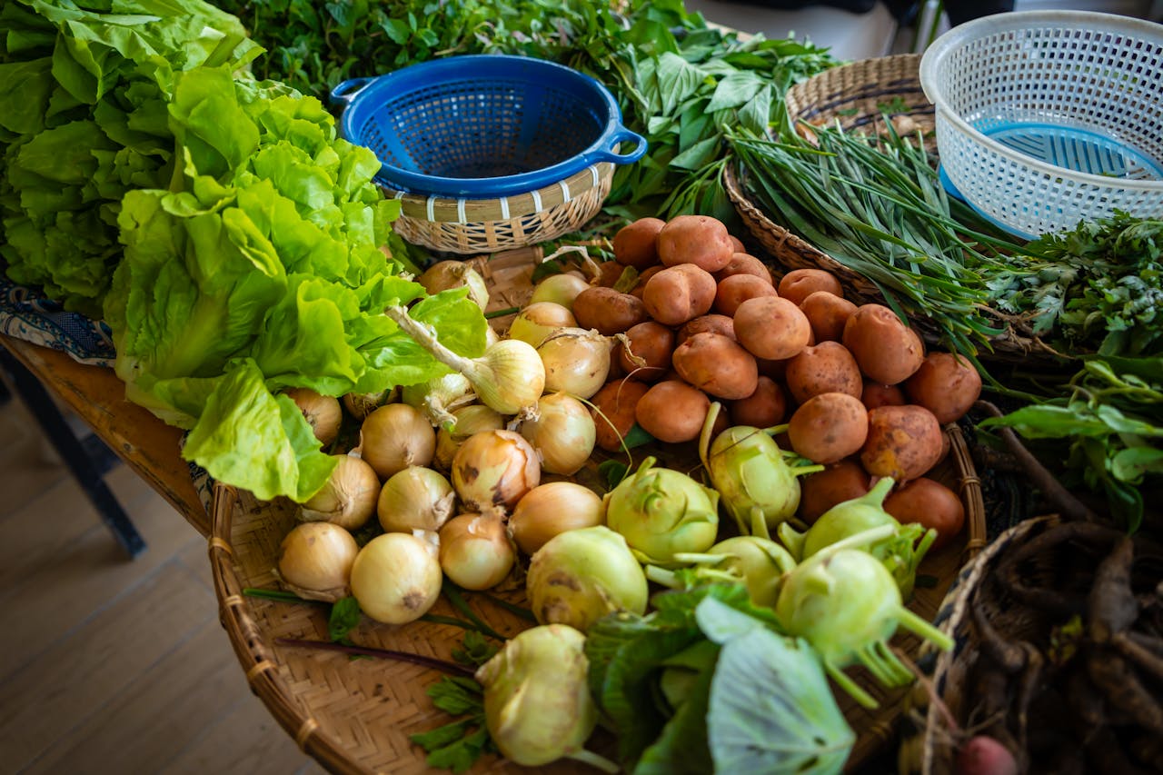 Colorful assortment of fresh vegetables including lettuce, potatoes, and onions on a market table.
